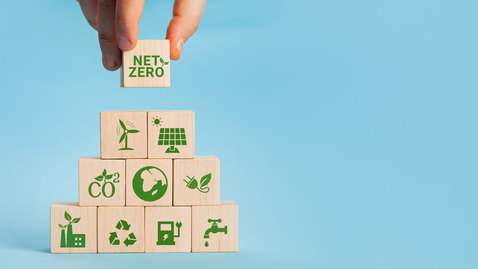 An image of 10 wooden blocks with the words net zero on one and then various sustainable graphics on the other blocks, including recycling, planting trees and others