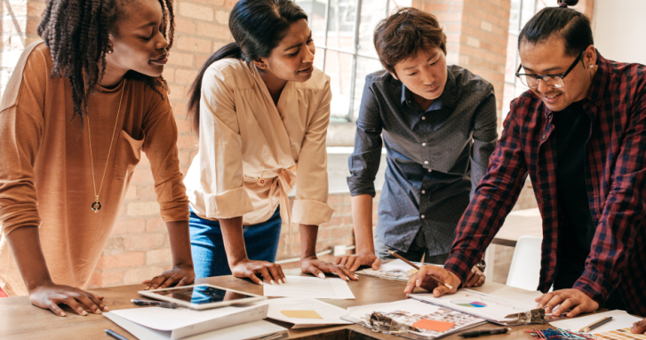 Four People stood around a table looking productive