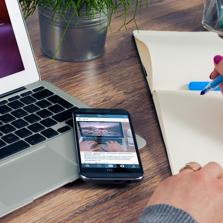 Person writing at desk in front of laptop